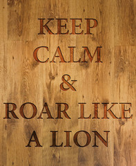 Text "Keep Calm & Roar Like a Lion" engraved in wooden background