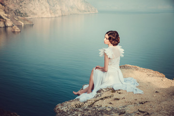 Beautiful bride posing on the coast with angelic dress.