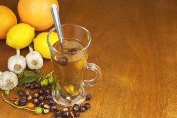 Traditional home treatment for colds and flu. Rosehip tea, garlic, honey and citrus. Hot tea with honey and lemon on a wooden tabletop. Home Pharmacy.
