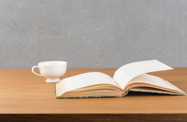 old book with a cup of coffee on wood table