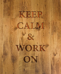 Text "Keep Calm & Work On" engraved in wooden background