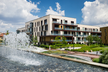 Block of flats in green public park with water steam during hot summer day