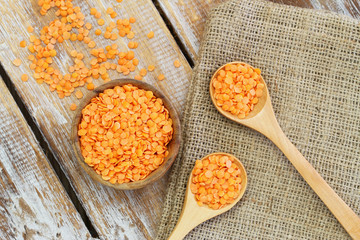 Uncooked red lentils in bowl and on wooden spoons
