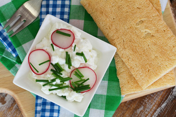 Cottage cheese in white bowl with chives and radish
