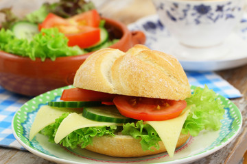 Bread roll with cheese, lettuce, tomato and cucumber, closeup
