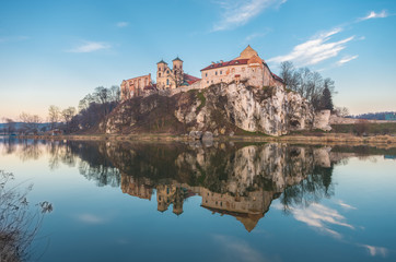 Fortified medieval Benedictine abbey in Tyniec, suburb of Krakow, reflecting in the still waters of the Vistula river in the evening
