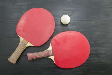 Two red table tennis rackets on dark background