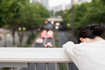 歩道橋の上で落ち込む女性