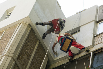 two high workers making repairs on a facade
