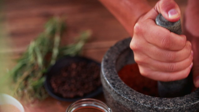 Hands using mortar and pestle to grind herbs and spices