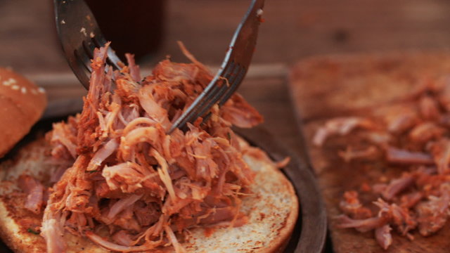 Delicious pulled pork being put on a burger bun 