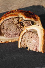 Pork pie sliced slate.
Slice of pork pie on a slate surface.