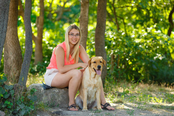 portrait of Beautiful young girl with her dog labrador retriever outdoor in summer beautiful park
