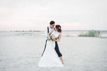 Bride and groom dancing barefoot on the sand