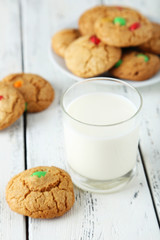 Cookies with colorful candy in plate on white wooden background