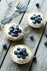Obraz na płótnie Canvas Dessert tartlets with blueberries on grey wooden background