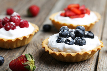Dessert tartlets with berries on grey wooden background