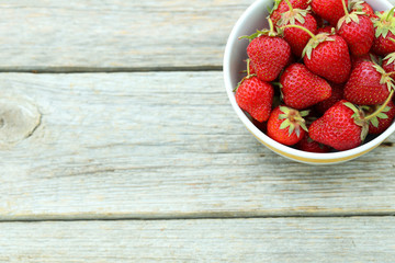 Strawberries berry in bowl on grey wooden background