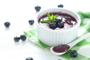 Delicious blueberry mousse in bowl on wooden table