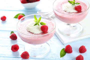 Sweet raspberry mousse in glass on blue wooden table