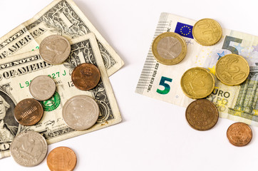 two groups of bills and coins of euros and dollars  face opposing. over white,
