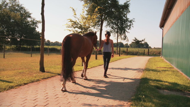 Girl leading her horse out of stables with vintage feel