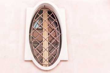 Fototapeta na wymiar Iron grating round window with wooden frame