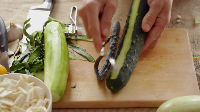 HD 1080 static: chef peeling cucumber using hand peeler; close up