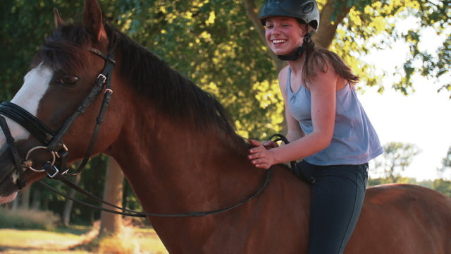 Girl on her horse with golden sun flare through leaves