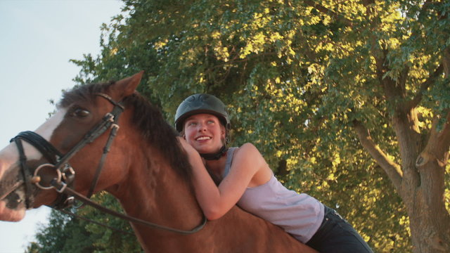 Girl leaning lovingly on her horse while riding in nature