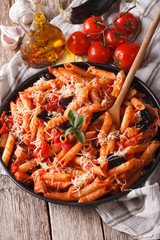 Penne with eggplant and tomatoes closeup and ingredients. Vertical
