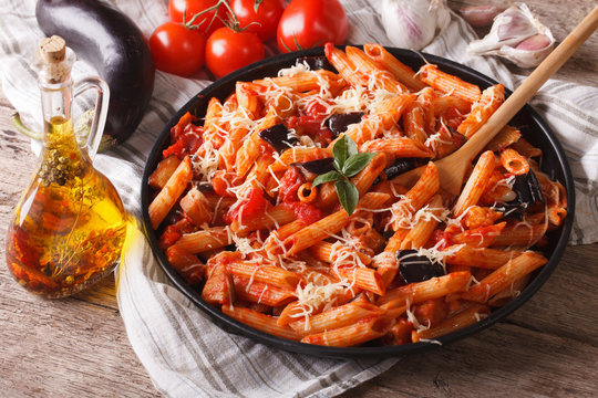 Penne with eggplant and tomatoes closeup and ingredients. horizontal
