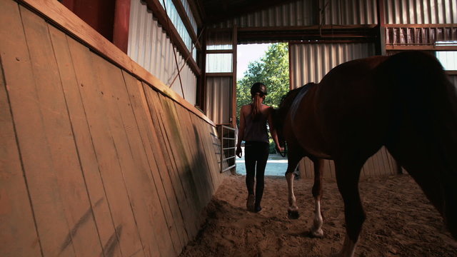 Girl leading her horse out of stables with vintage feel
