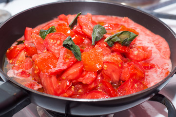 Sugo di pomodoro fresco in cottura, padella sul fuoco, fornelli