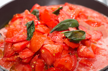 Sugo di pomodoro fresco in cottura, padella sul fuoco, fornelli