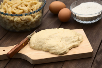 Preparing Hungarian Nokedli or Galuska out of an egg-flour dough. The dough gets cut in small pieces into boiling water, and is served as a side dish (Selective Focus, Focus one third into the dough)