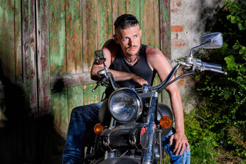 Tough guy with his bike in front of a green barn door