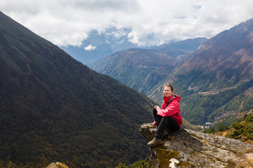 Naklejka premium Young woman tourist sitting mountain edge rock. Nepal.