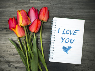 Fototapeta premium tulip bouquet and notepad with words 