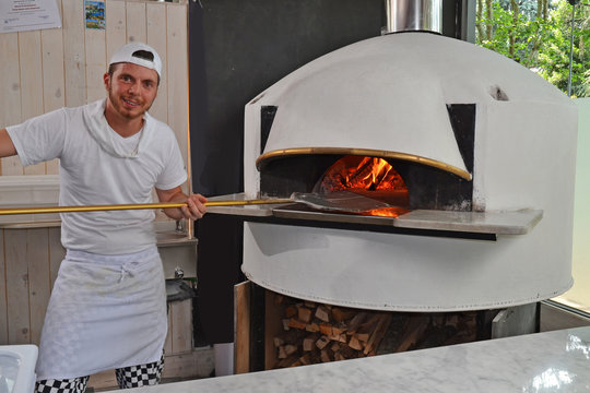 Panadero cocinando pizza en un horno a 