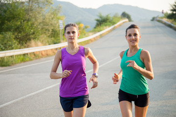 due donne giovani che corrono per strada al tramonto