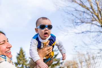 Nice baby with blue googles raised in air