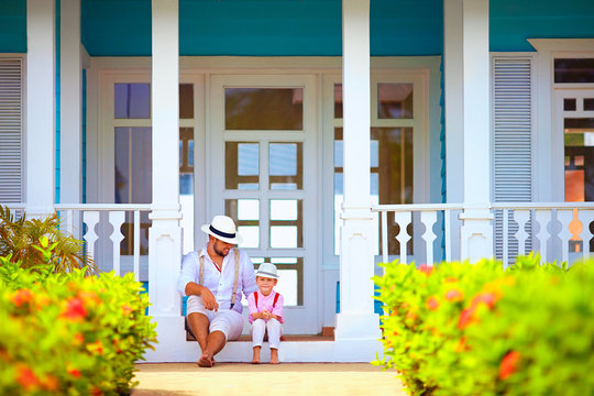 cute father and son sitting on porch, caribbean exterior