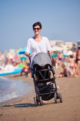 mother walking on beach and push baby carriage