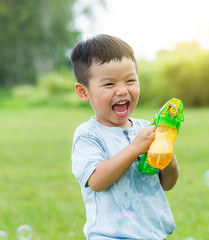 Thrilled boy play bubble blower at park