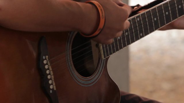 close-up of man playing guitar indoor