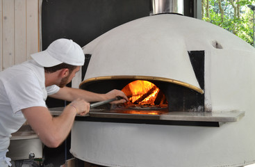 Panadero cocinando pizza en un horno a leña