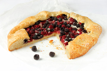 Open pie with black and red raspberries on a white background