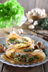 Pancakes with creamy mushrooms on wooden background