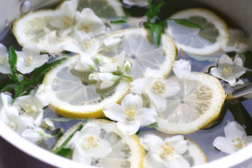 Cold refreshing summer drink with mint and slices of lemon in pan close up